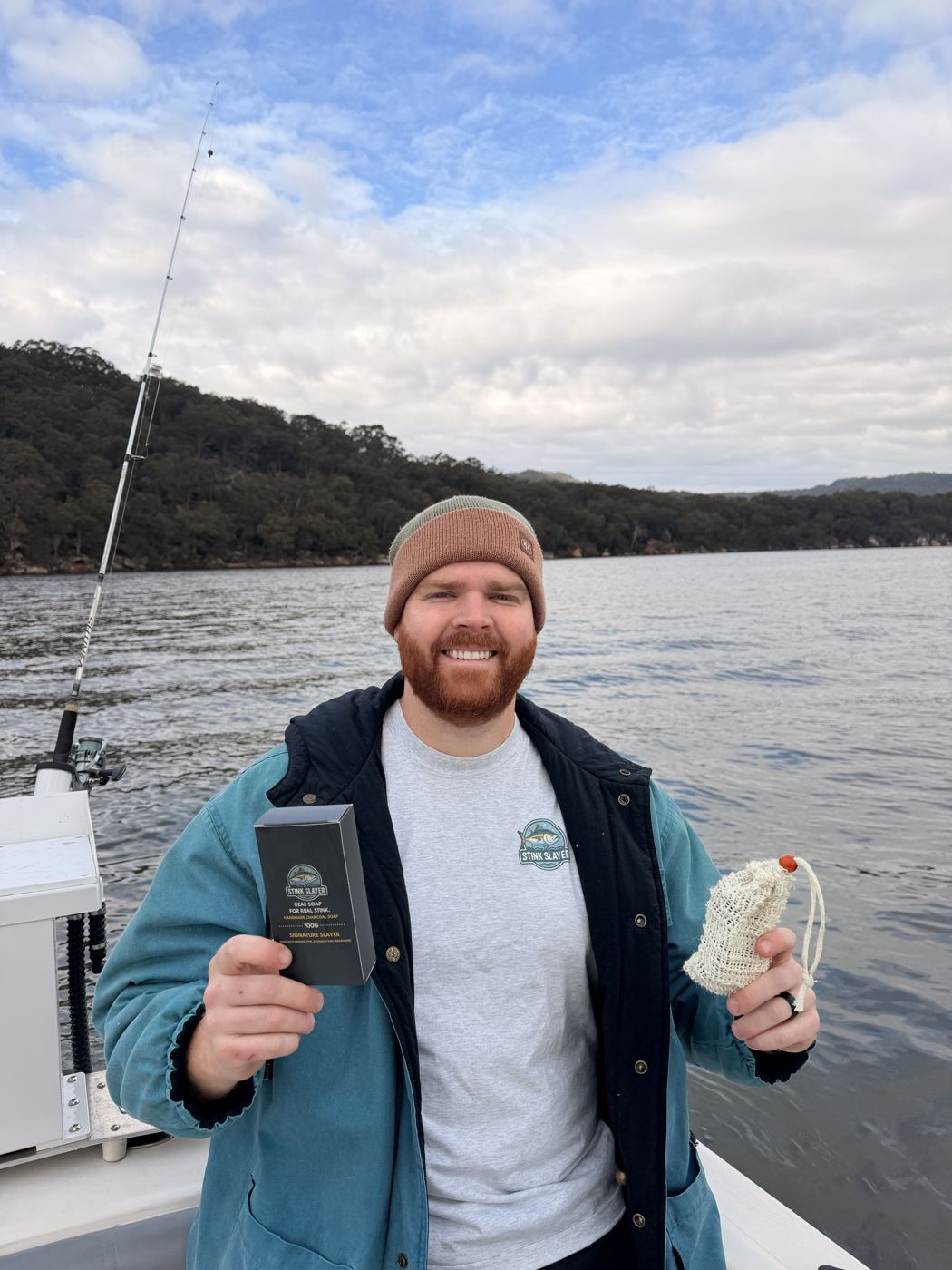 Mitch on his boat holding a Stink Slayer box and soap bag